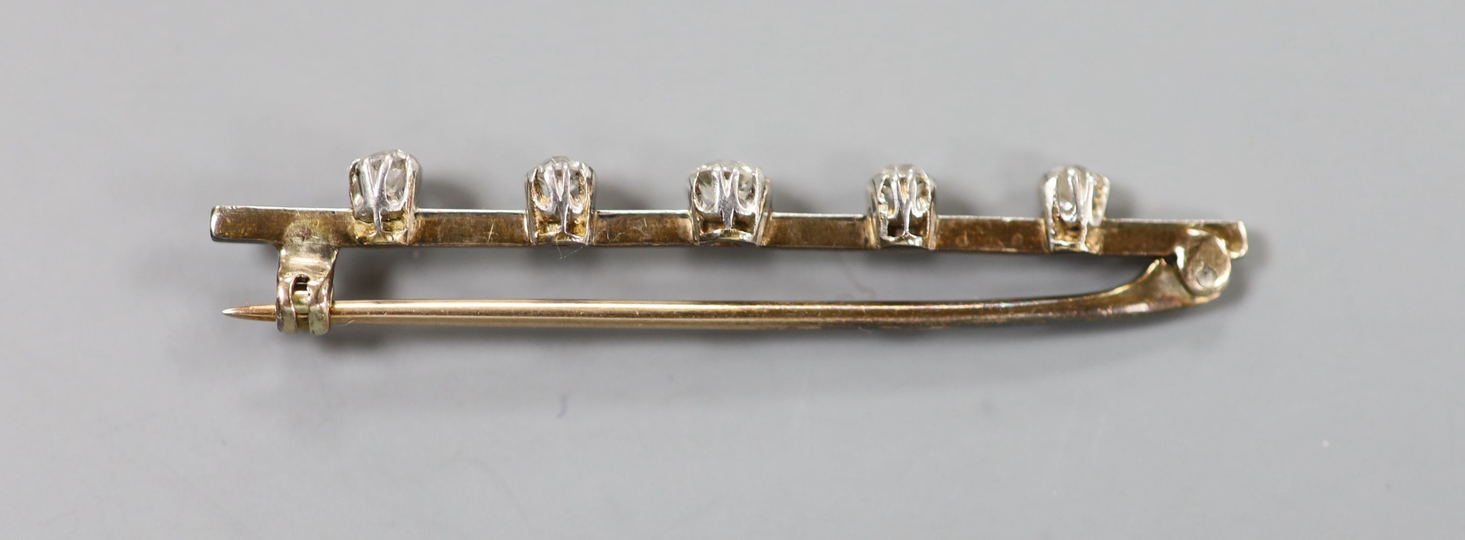 A yellow metal and graduated five stone diamond set bar brooch, 50mm, gross weight 3.7 grams.